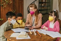 Kindergarten teacher teaching three kids to read